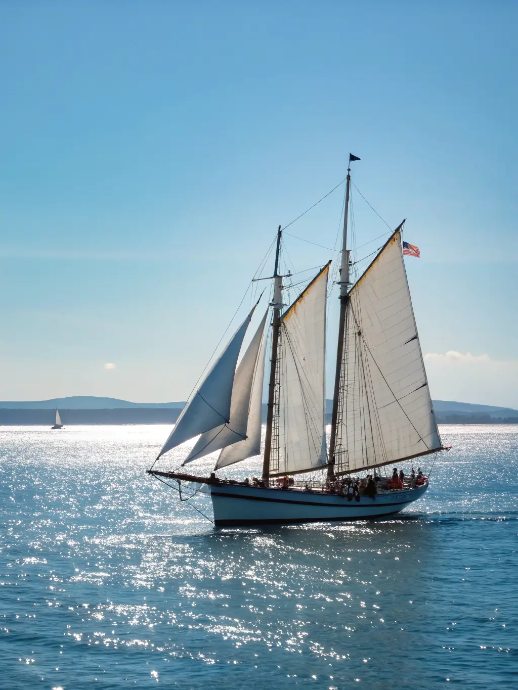 A wide shot of a fully restored classic yacht sailing on a calm lake, showcasing the beauty and elegance of a restored vessel.